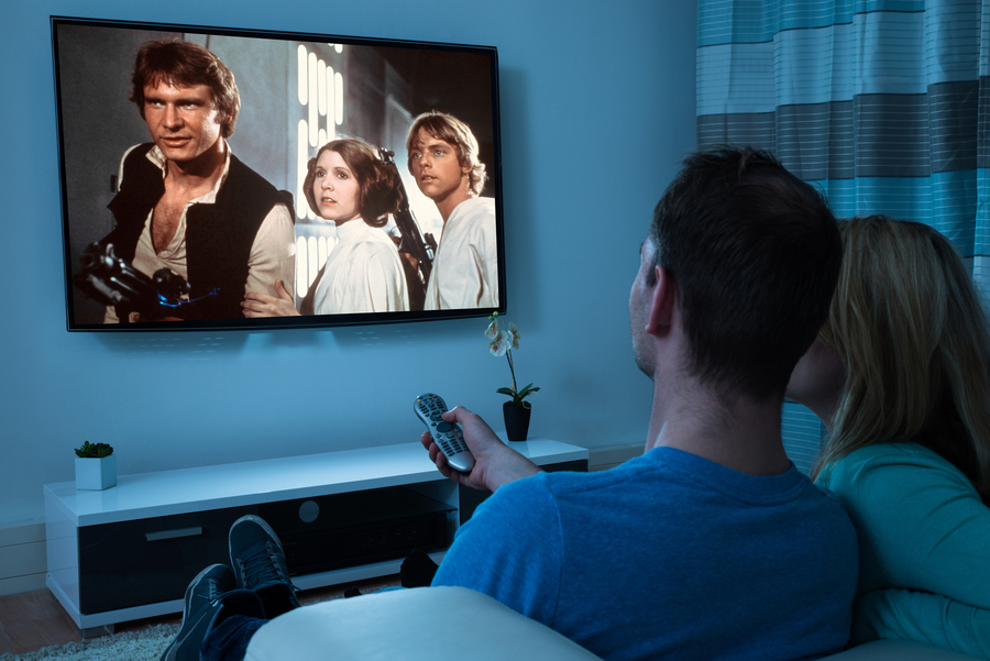 A couple sits in front of a TV to watch the movie Star Wars.