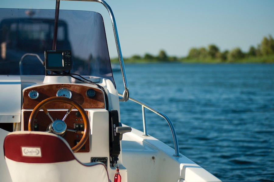 Photo of the captain's seat and steering wheel of yacht, with brown and white interior.