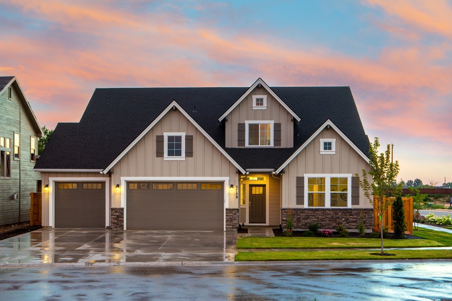 Photo of a brown and tan painted house from the road, beautifully lit both inside and out.