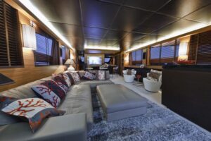A media room in a yacht with a sectional, seating, and TV.
