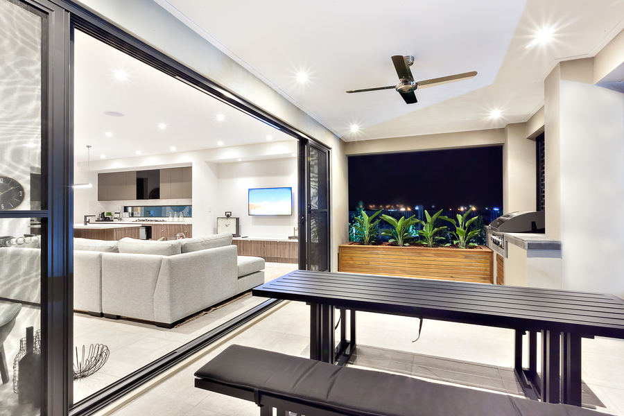 A white dining room with a rectangular table, recessed lights, and in-ceiling Sonance speakers.