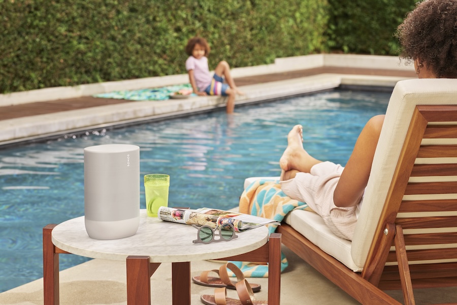 A woman listens to music while watching a child in the swimming pool.